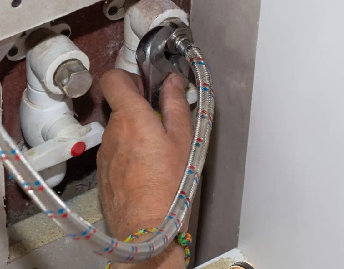 Braided stainless flexible supply connector being fitted onto shut-off valves during a bathroom rough-in