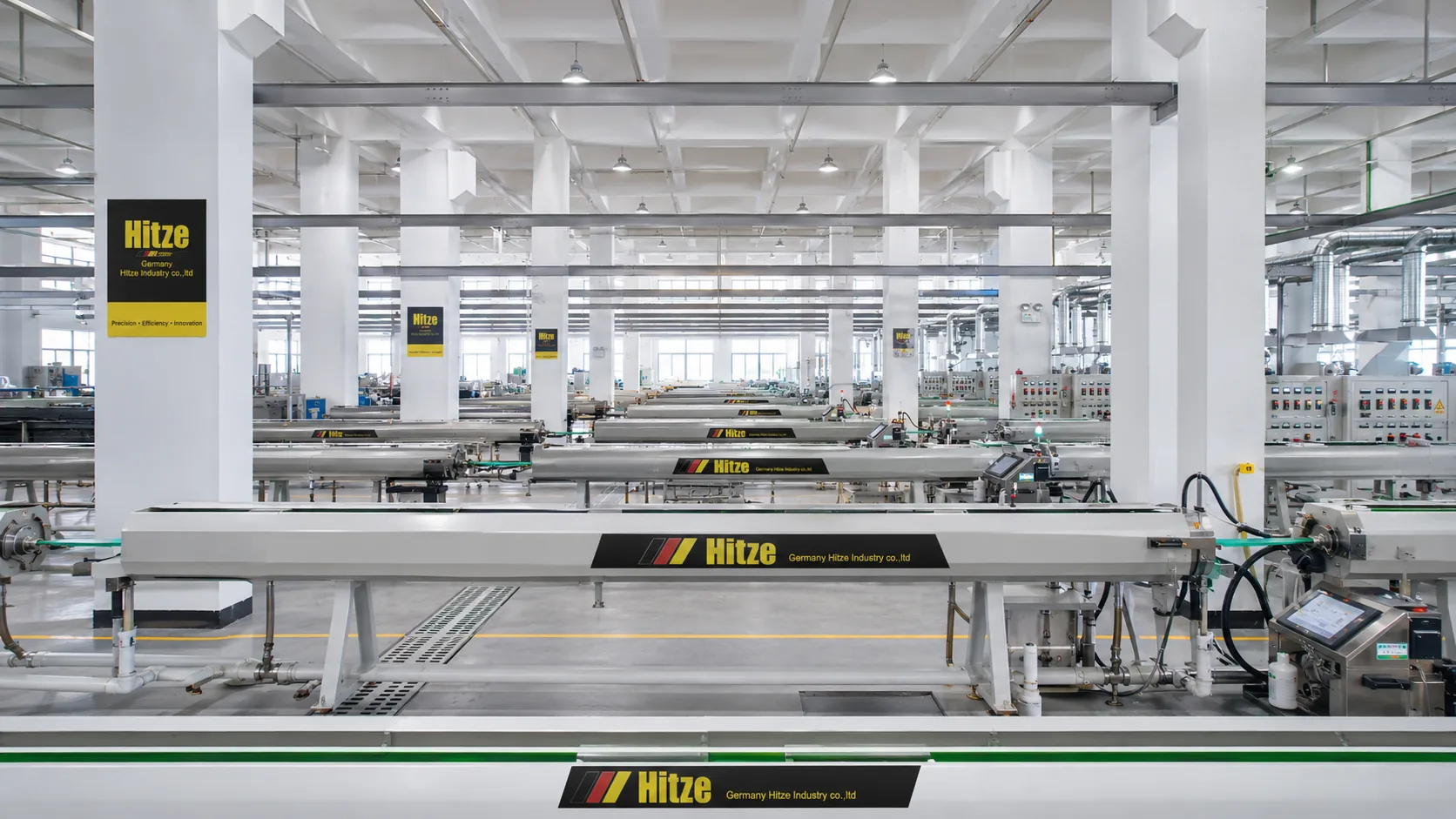 Wide view of a pipe production hall with parallel extrusion lines and electrical control cabinets running the length of the floor during a factory audit walk-through
