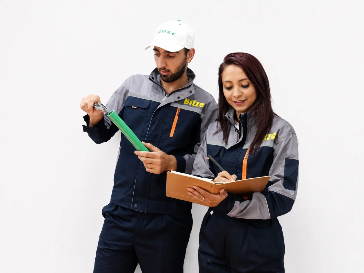 Two Hitze workers cutting and inspecting green PP-R pipe on the production line