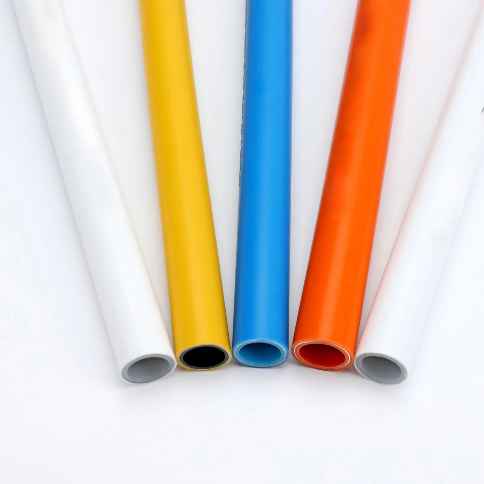 Multilayer pipe in white, yellow, blue and orange laid side by side across the 16mm to 32mm size range
