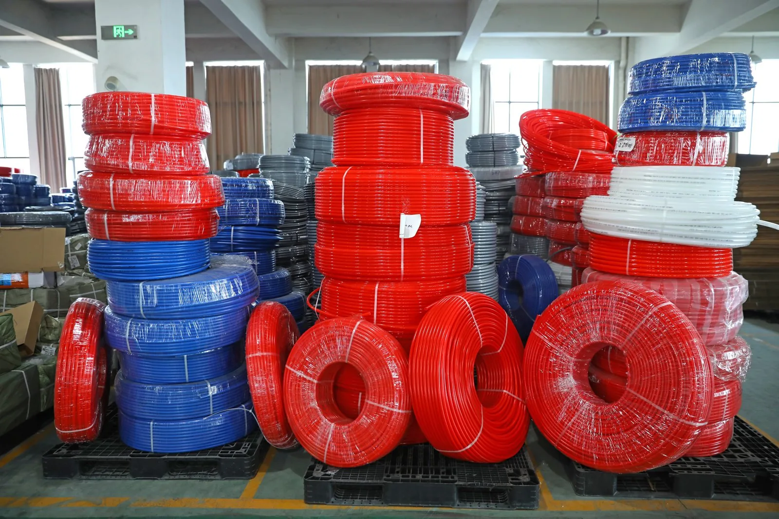 Pallets of red, blue and white PEX heating and plumbing coils stocked container-ready in a warehouse, the kind of shipment that clears customs only with a complete certification pack