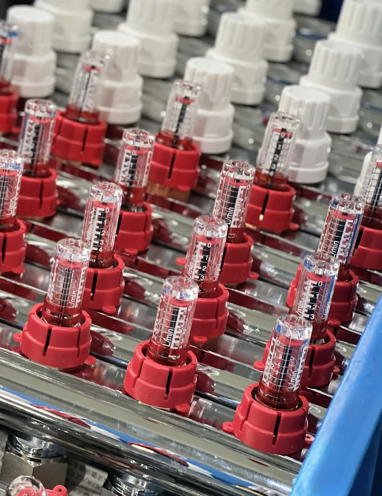 Rows of clear sight-gauge flow meters with 0 to 2.5 L/min scales and coloured caps on Hitze manifold flow bars
