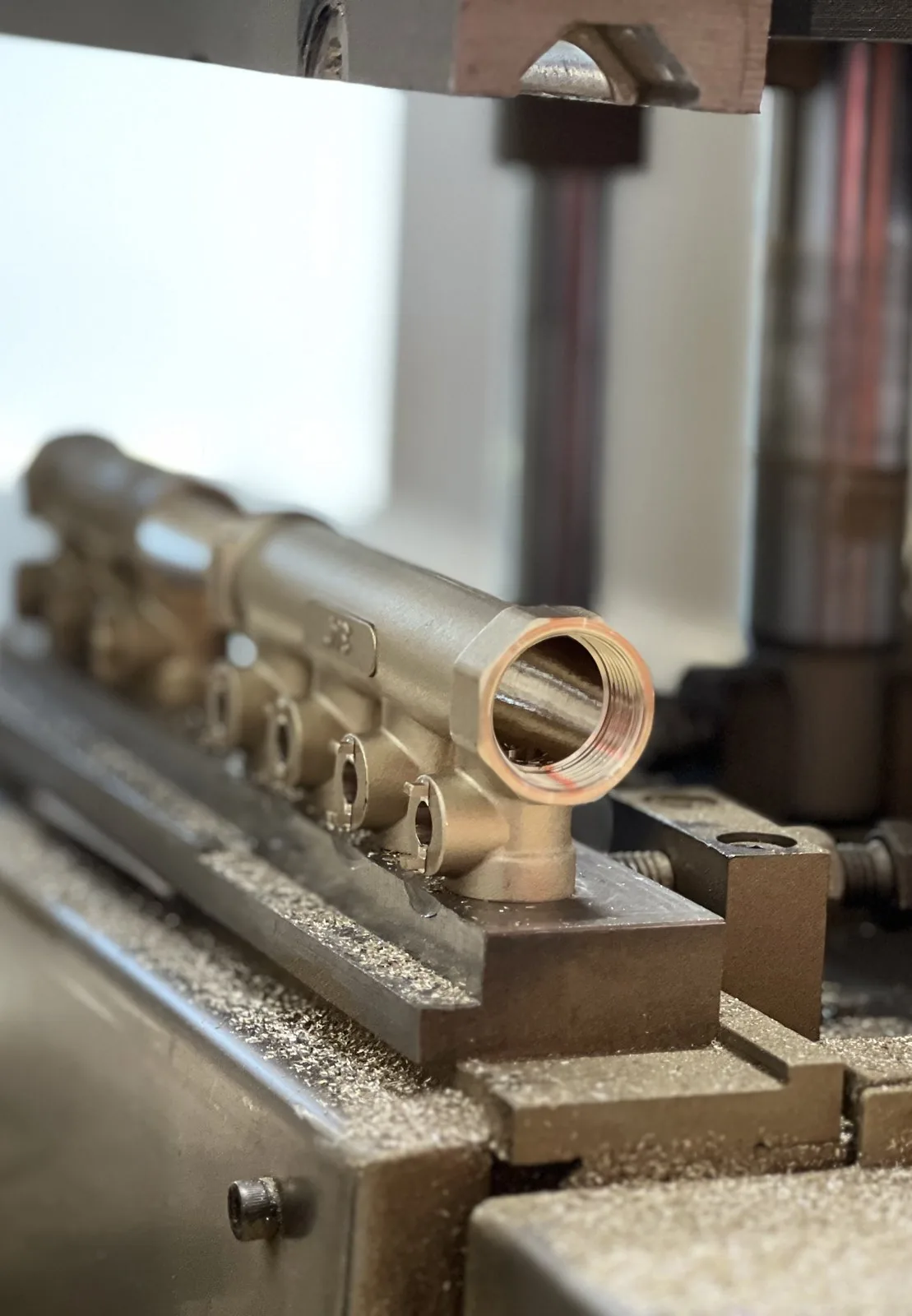Machined manifold body on a lathe showing the threaded main-body bore and wall thickness